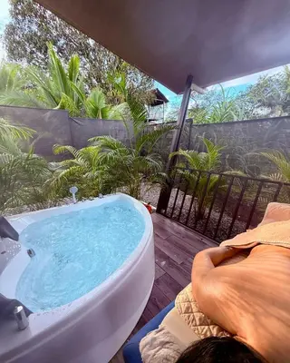 a bath tub sitting on a deck with a person laying down at Arenal Star Luxury Studios with Private Jacuzzi in Fortuna