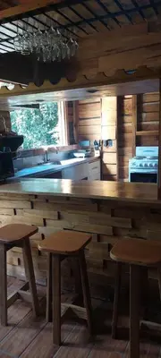 a kitchen with a wooden counter and two stools at Cabaña Las Palmeras, Pura Vida in Linda Vista