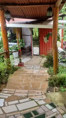 a stone walkway in front of a house with a roof at Cabaña las Palmeras Pura Vida!! in Linda Vista