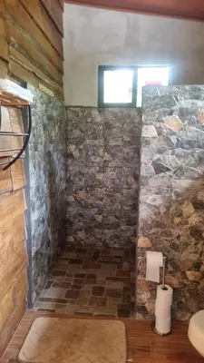 a bathroom with a stone wall and a window at Cabaña las Palmeras Pura Vida!! in Linda Vista