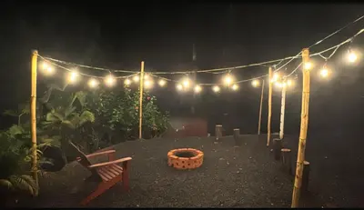 a garden with lights and a bench in the dark at Cabaña las Palmeras Pura Vida!! in Linda Vista