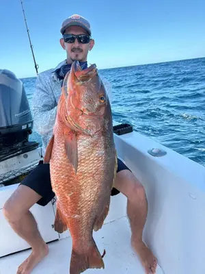 a man sitting on a boat holding a large fish at Jungle Overnight