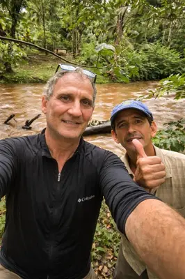 two men standing next to a river with a stick at Jungle Overnight