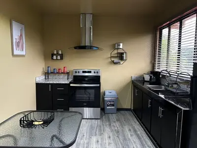 a kitchen with black cabinets and a table and a stove at Villa Paraíso in Quepos