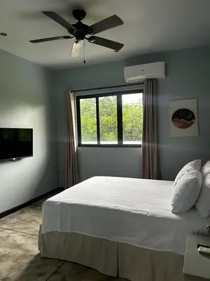 a bedroom with a bed with a ceiling fan and a window at Villa Paraíso in Quepos