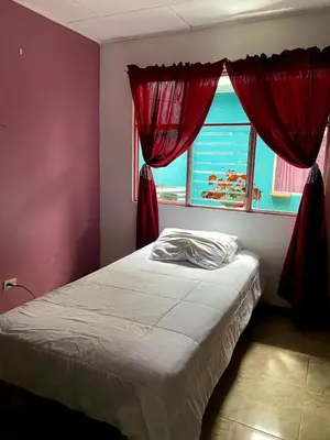 a bedroom with a bed with red curtains and a window at Hermosa House Tibas