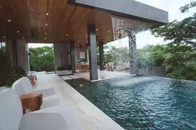 an infinity pool in a house with white furniture at Casa Dominick - Luxury a short walk from the sea in Nosara