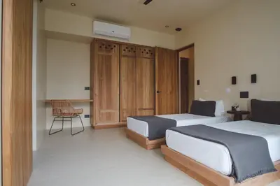 a bedroom with two beds and a chair in it at Casa Dominick - Luxury a short walk from the sea in Nosara