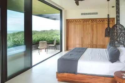 a bedroom with a bed and a balcony with a view at Casa Dominick - Luxury a short walk from the sea in Nosara