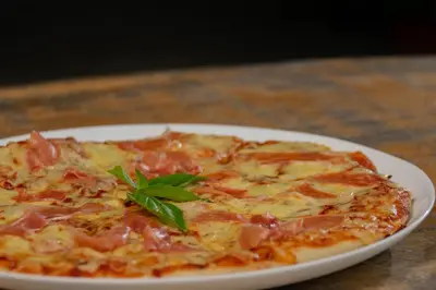 a pizza on a white plate on a table at Pejivalle Lodge paz y naturaleza en un solo lugar in Humo