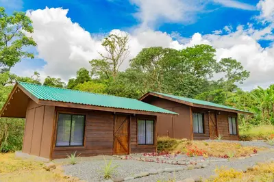 a small wooden cabin with a green roof at Pejivalle Lodge paz y naturaleza en un solo lugar in Humo