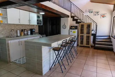 a kitchen with a counter with stools and a staircase at Hostel Cocos B&B in Alajuela City