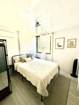 a white bedroom with a bed and a window at Piyiyo House 5 minutes from the beach walking in Uvita