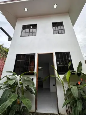 a white house with a door and some plants at Minicasita Blanca in Uvita