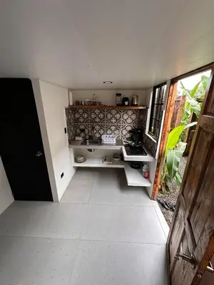 a room with a kitchen with a sink and a door at Minicasita Blanca in Uvita