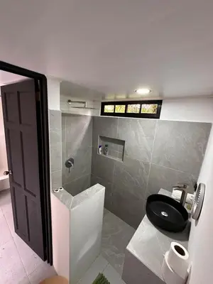 a bathroom with a black toilet and a shower at Minicasita Blanca in Uvita
