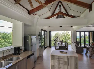 a kitchen with a vaulted ceiling and a living room at Tulemar Resort in Manuel Antonio