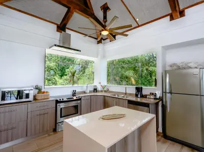a kitchen with stainless steel appliances and wooden cabinets at Tulemar Resort in Manuel Antonio