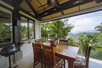 a dining room with a table and chairs and a large window at Tulemar Resort in Manuel Antonio