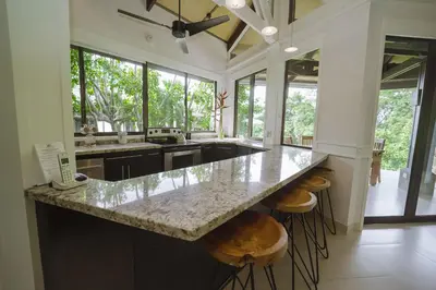 a large kitchen with a large island with bar stools at Tulemar Resort in Manuel Antonio