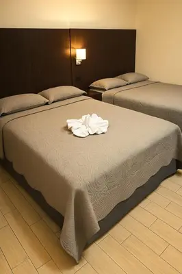two beds in a hotel room with towels on the bed at Hotel Boutique 4 Estancias in San Ramón