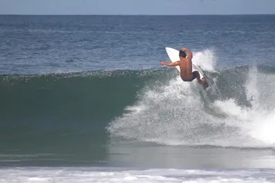 a man riding a wave on a surfboard in the ocean at Tropical House Relaxation with Private Pool in Santa Cruz