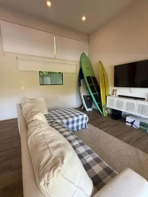 a living room with a couch and surfboards on the wall at Tropical House Relaxation with Private Pool in Santa Cruz