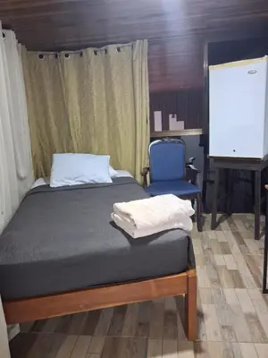 a bedroom with a bed and a chair and a screen at The cheap bed, by Natural Pacific Suites in Tapantí