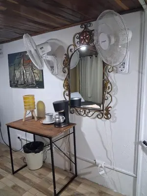 a room with a table with a mirror and fan at The cheap bed, by Natural Pacific Suites in Tapantí