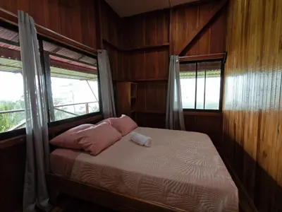 a bedroom with a bed with pink pillows and a window at Cabaña vista al miravalles in Bijagua