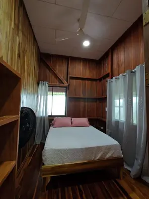 a bedroom with a bed with wooden walls and a window at Cabaña vista al miravalles in Bijagua