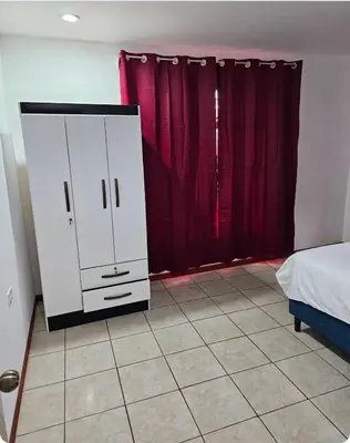 a bedroom with a white cabinet and red curtains at Habitación privada con baño privado en Pérez Zeledón in San Isidro