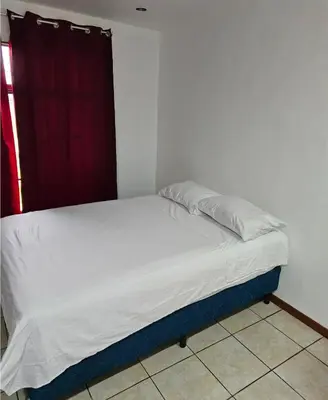 a bed in a bedroom with a red curtain at Habitación privada con baño privado en Pérez Zeledón in San Isidro