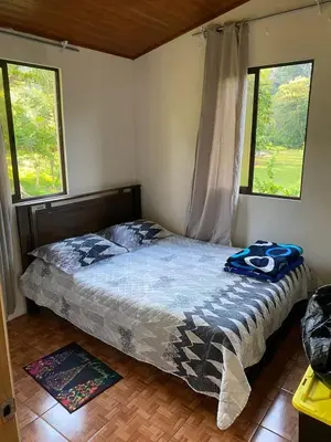 a bed in a bedroom with two windows at Cabaña Las Vegas de Acosta in San Ignacio