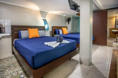 two beds in a room with blue and orange pillows at Hotel Casa del Arbol Manuel Antonio in Quepos