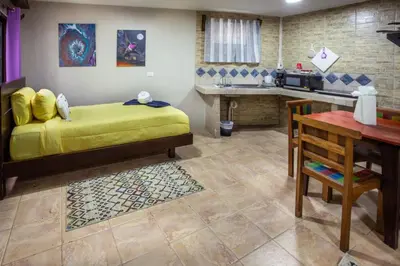 a room with a bed and a table and a kitchen at Hotel Casa del Arbol Manuel Antonio in Quepos