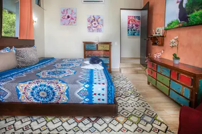 a bedroom with a king sized bed and a dresser at Hotel Casa del Arbol Manuel Antonio in Quepos
