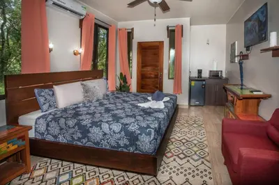 a bedroom with a bed and a red couch at Hotel Casa del Arbol Manuel Antonio in Quepos