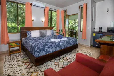 a bedroom with a bed and a couch and windows at Hotel Casa del Arbol Manuel Antonio in Quepos