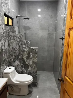 a bathroom with a toilet and a stone wall at Cabinas Vif Guanacaste