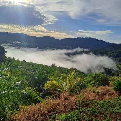 a view of a mountain with clouds in the valley at Casa de montaña in Quepos