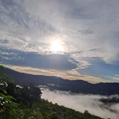 a view of the sun rising over a valley of clouds at Casa de montaña in Quepos