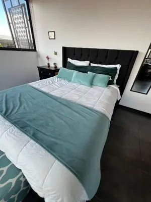 a bedroom with a large bed with blue and white sheets at 5 min from AirPort SJO OASIS LOFT in Alajuela City
