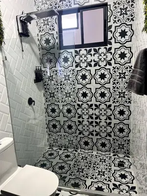 a bathroom with a black and white tile wall at 5 min from AirPort SJO OASIS LOFT in Alajuela City