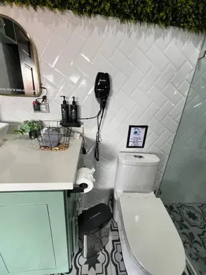 a bathroom with a toilet and a phone on the wall at 5 min from AirPort SJO OASIS LOFT in Alajuela City