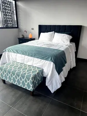 a bedroom with a large bed with a green and white comforter at 5 min from AirPort SJO OASIS LOFT in Alajuela City