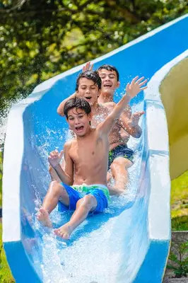 three young boys riding on a water slide at Vida Aventura Ranch in Tanques