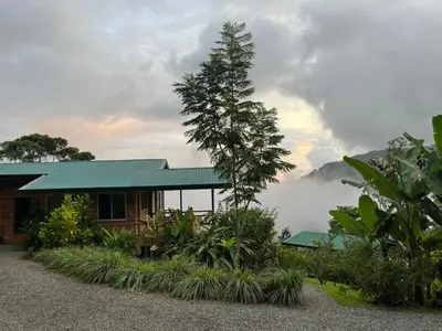 a house with a green roof with a mountain in the background at El Verde Pacifico in San Luis
