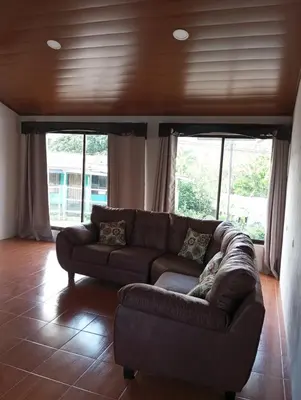 a brown couch in a living room with windows at Ordoñez in Bijagua