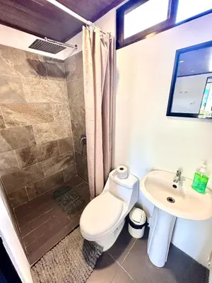 a bathroom with a shower and a toilet and a sink at Mini House 2 in Uvita